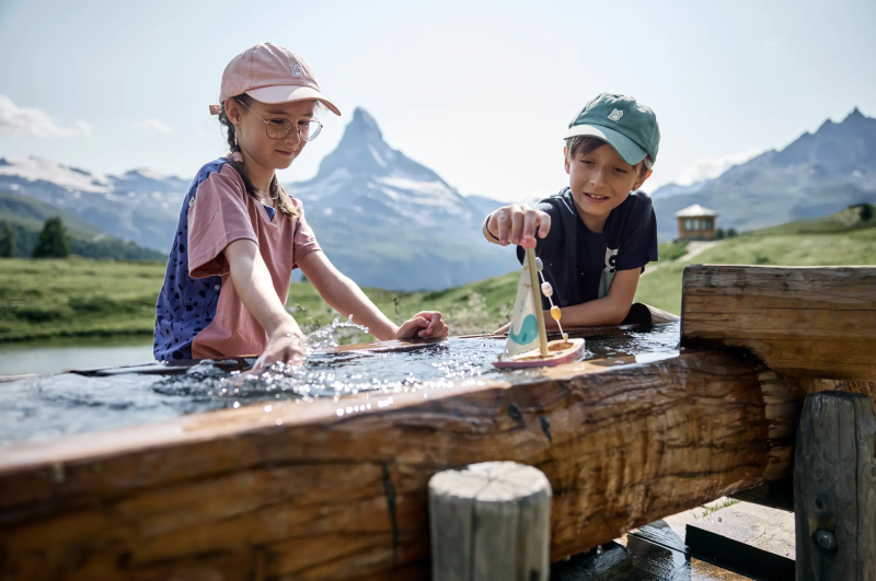 Kind met mountainbike bij een houten hek in Zermatt