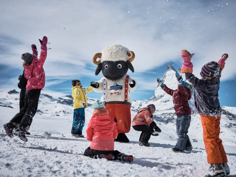 Kinderen zwaaien bij een robotmascotte in Zermatt